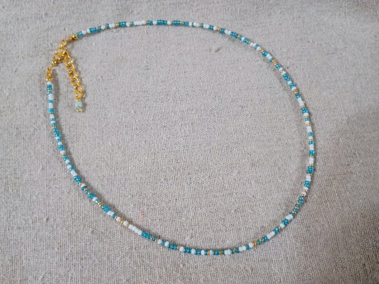 Beaded necklace with blue and white beads on a gray surface