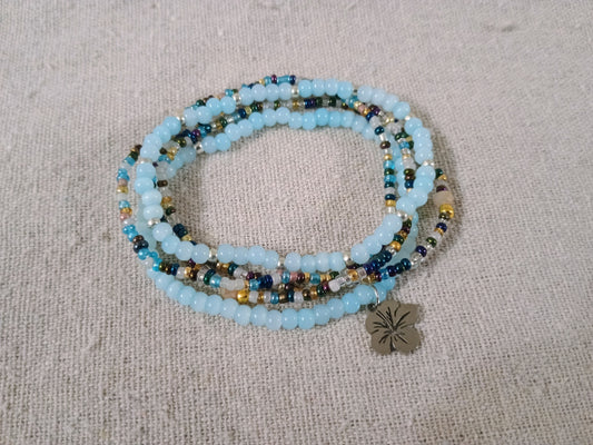 Beaded bracelet with a metal charm on a textured beige surface