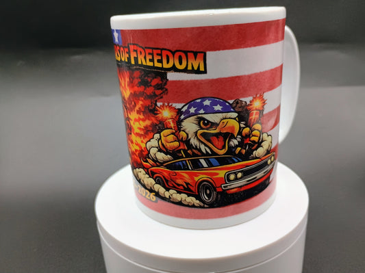 A white ceramic mug featuring a patriotic graphic design with the words 'Proud of Freedom' in yellow and black, set against red and white stripes. The design includes a cartoon eagle wearing an American flag bandana and roaring over a red muscle car with flames.
