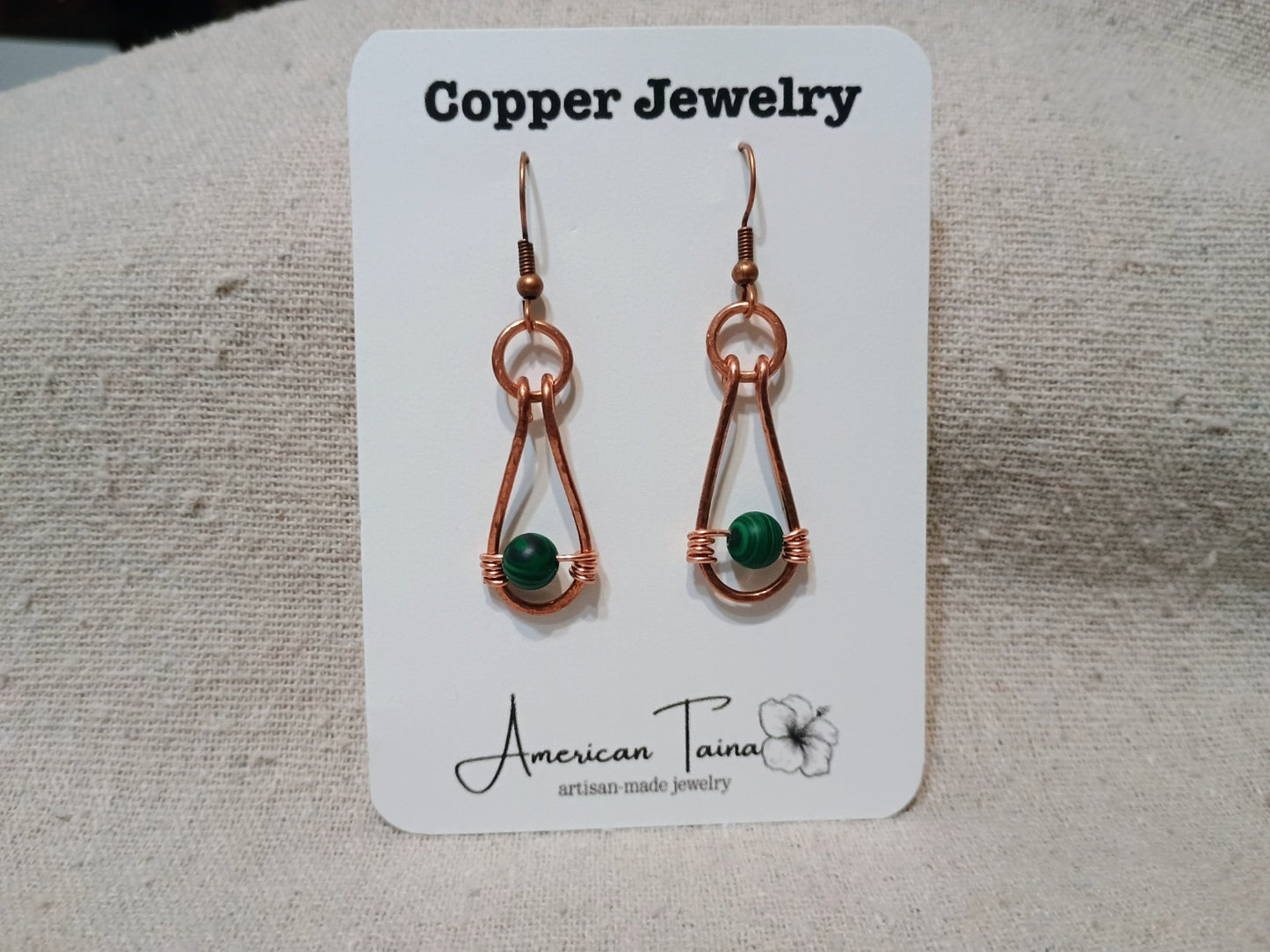 Copper teardrop earrings with wire-wrapped malachite bead on American Taina jewelry card