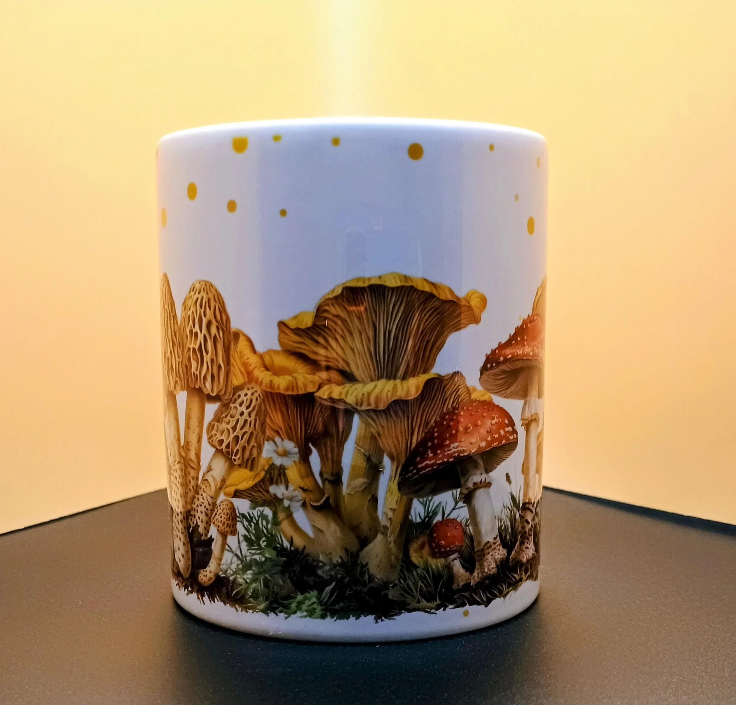 White ceramic mug with detailed illustration of various mushrooms and foliage on black table
