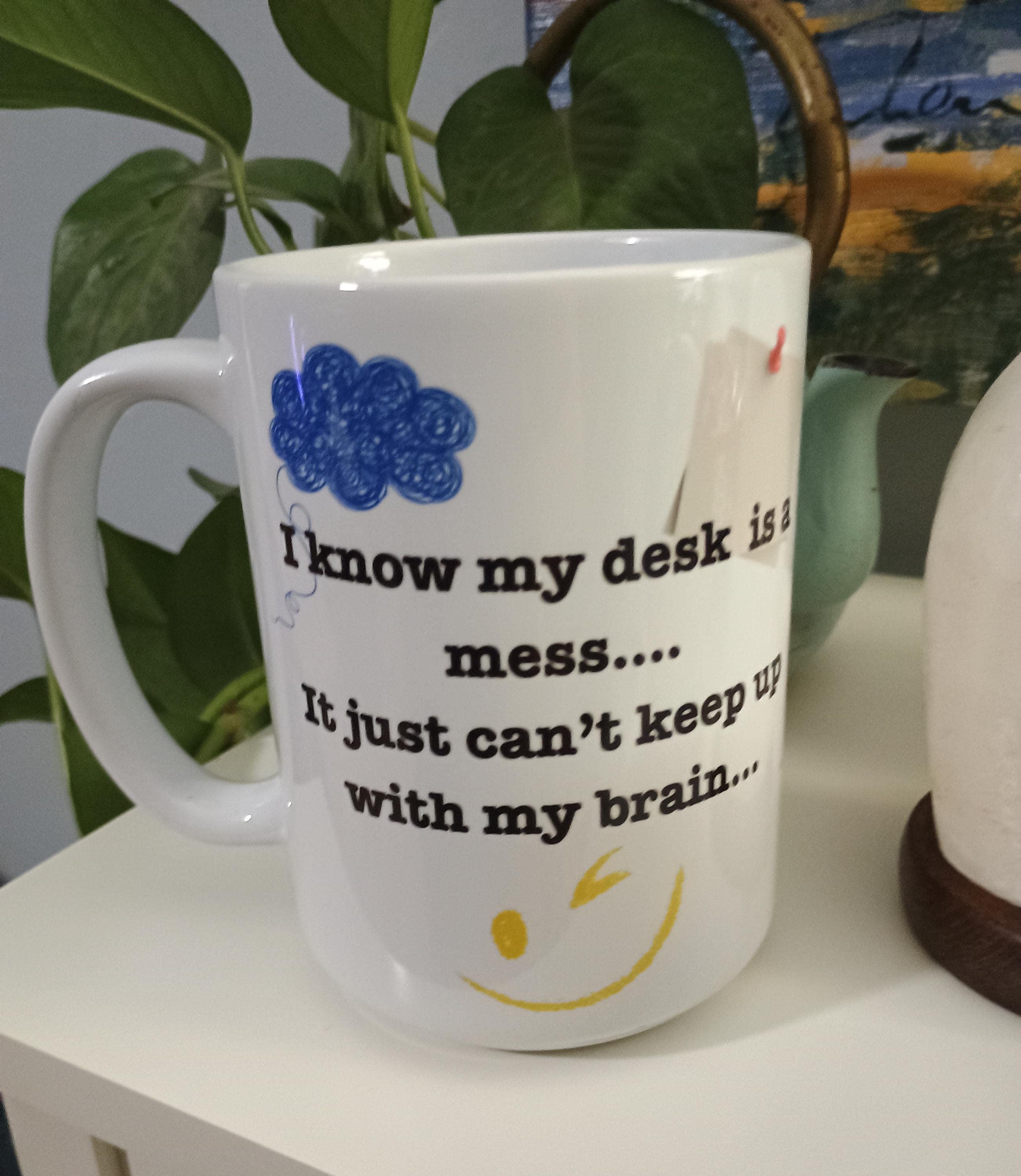 White coffee mug with quote I know my desk is a mess, it just can't keep up with my brain and a winking smiley face