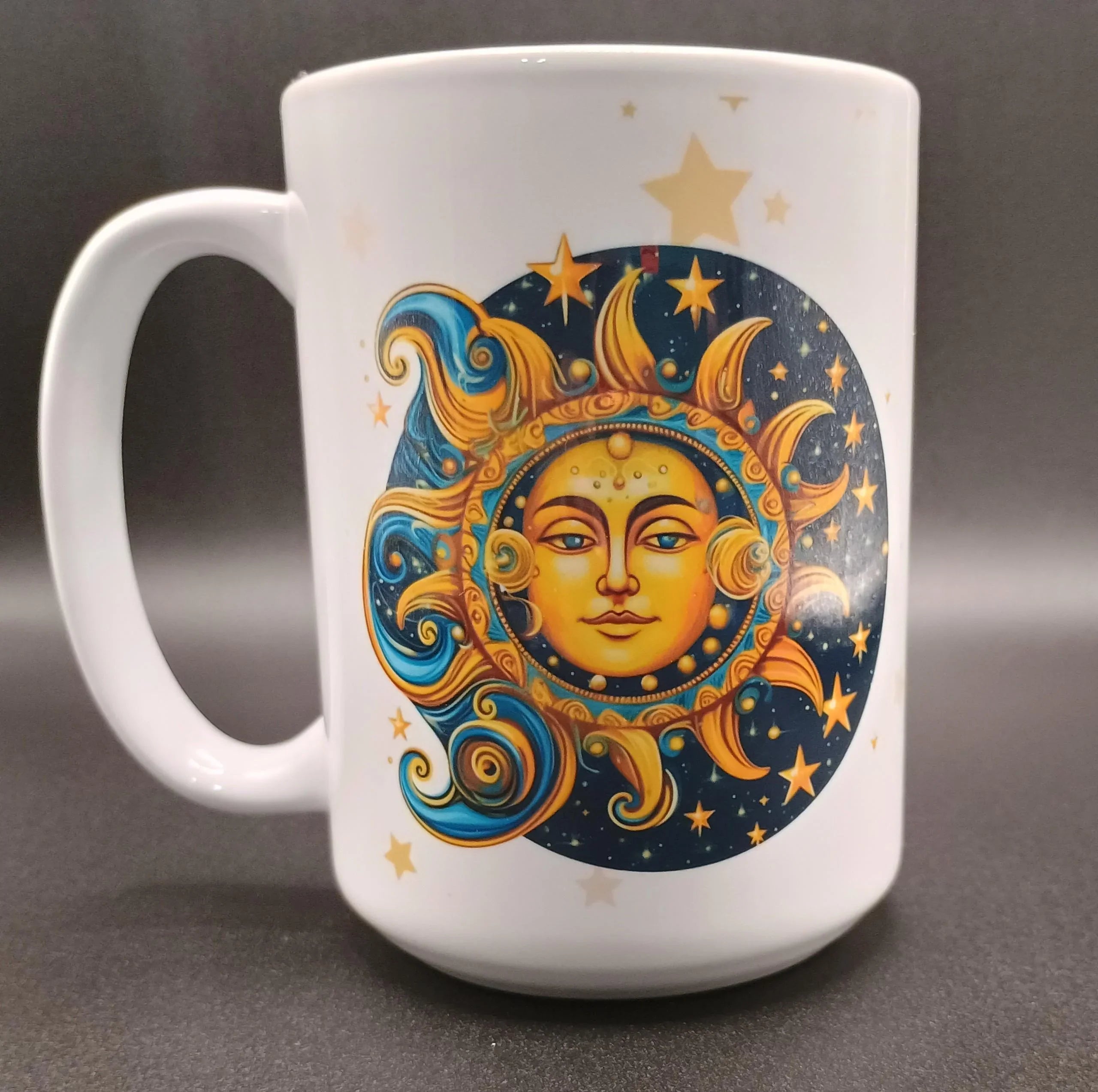 White ceramic mug with artistic sun and moon face design in blue and gold tones