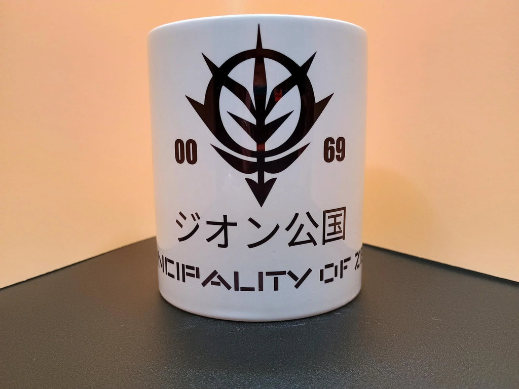 White ceramic mug with black Zeon emblem from Gundam and text in Japanese and English