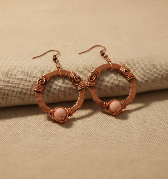 Hammered copper hoop earrings with natural rhodonite stone and wire-wrapped coil detail