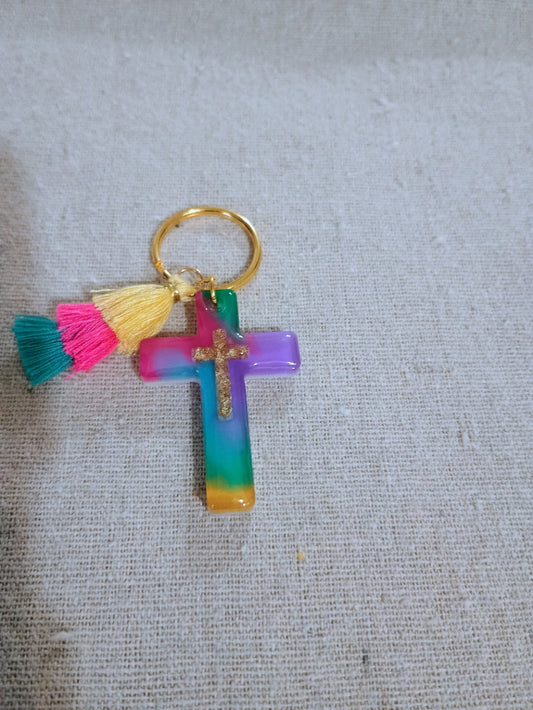 Colorful cross keychain with tassels on a textured gray background