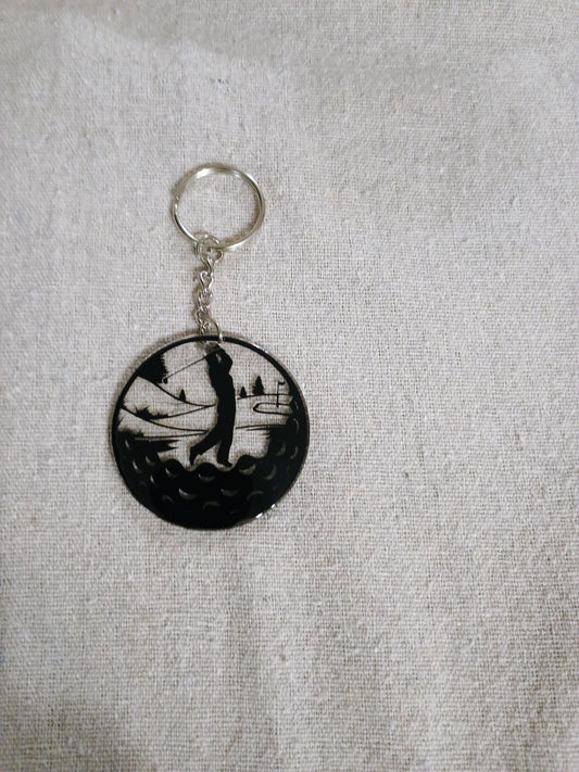 Keychain with a black and white design of a person playing golf on a gray fabric background