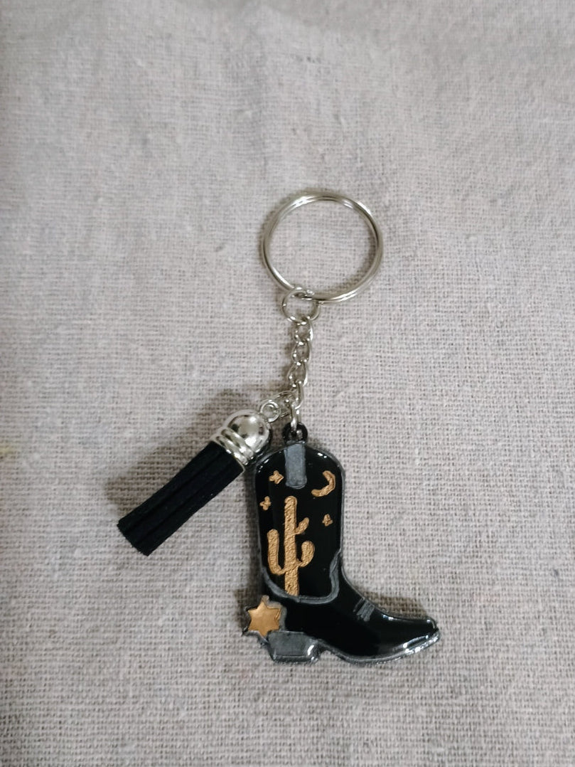 Keychain with black boot and anchor design on a gray fabric background