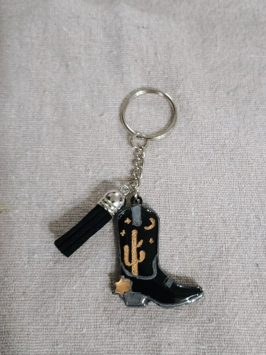 Keychain with black boot and anchor design on a gray fabric background