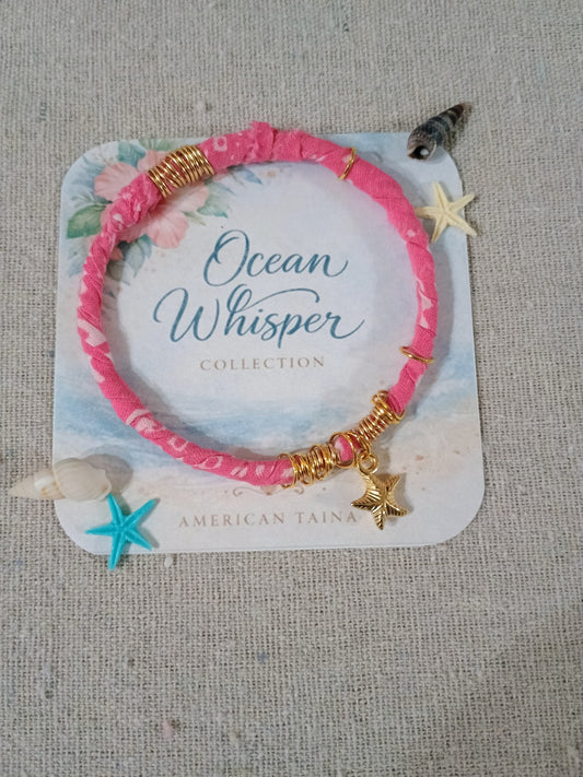 Pink bracelet with star charms on a 'Ocean Whisper Collection' card against a textured gray background