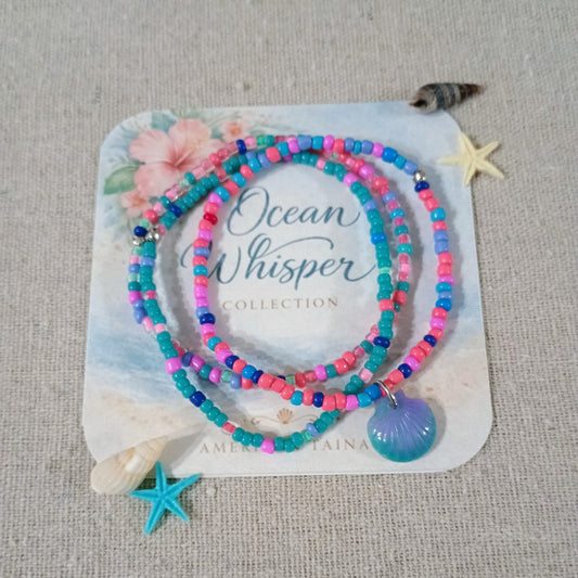 Set of colorful beaded bracelets with a blue pendant on a 'Ocean Whisper' branded card.