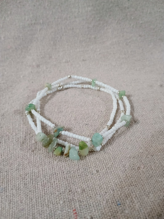 Beaded bracelet with green stones on a textured beige background