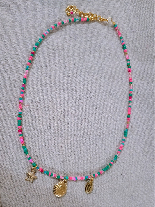 Colorful beaded necklace with shell and starfish charms on a textured surface