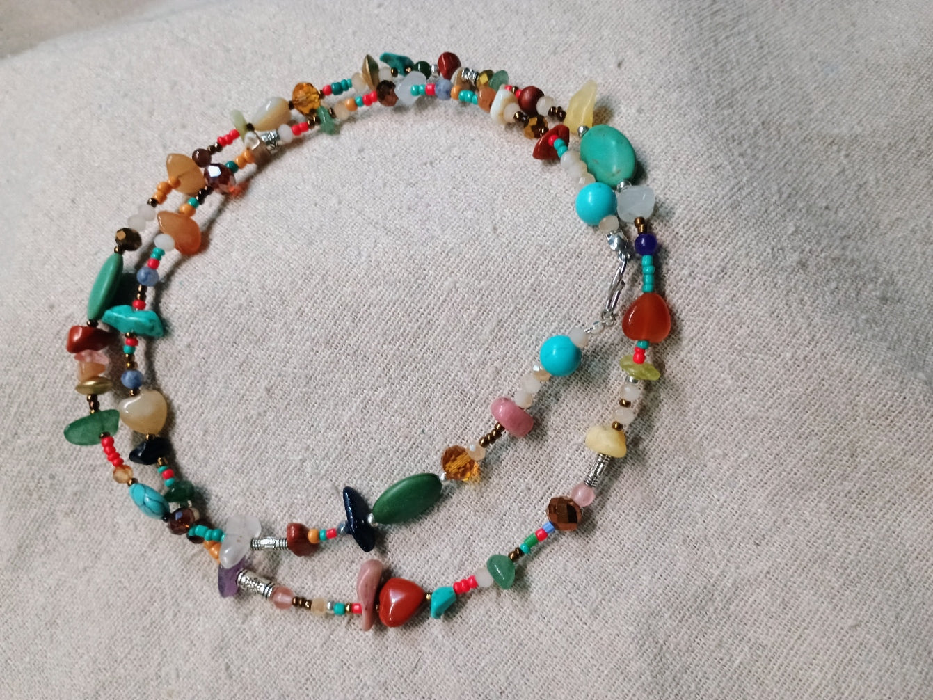 Colorful beaded necklace on a textured fabric background