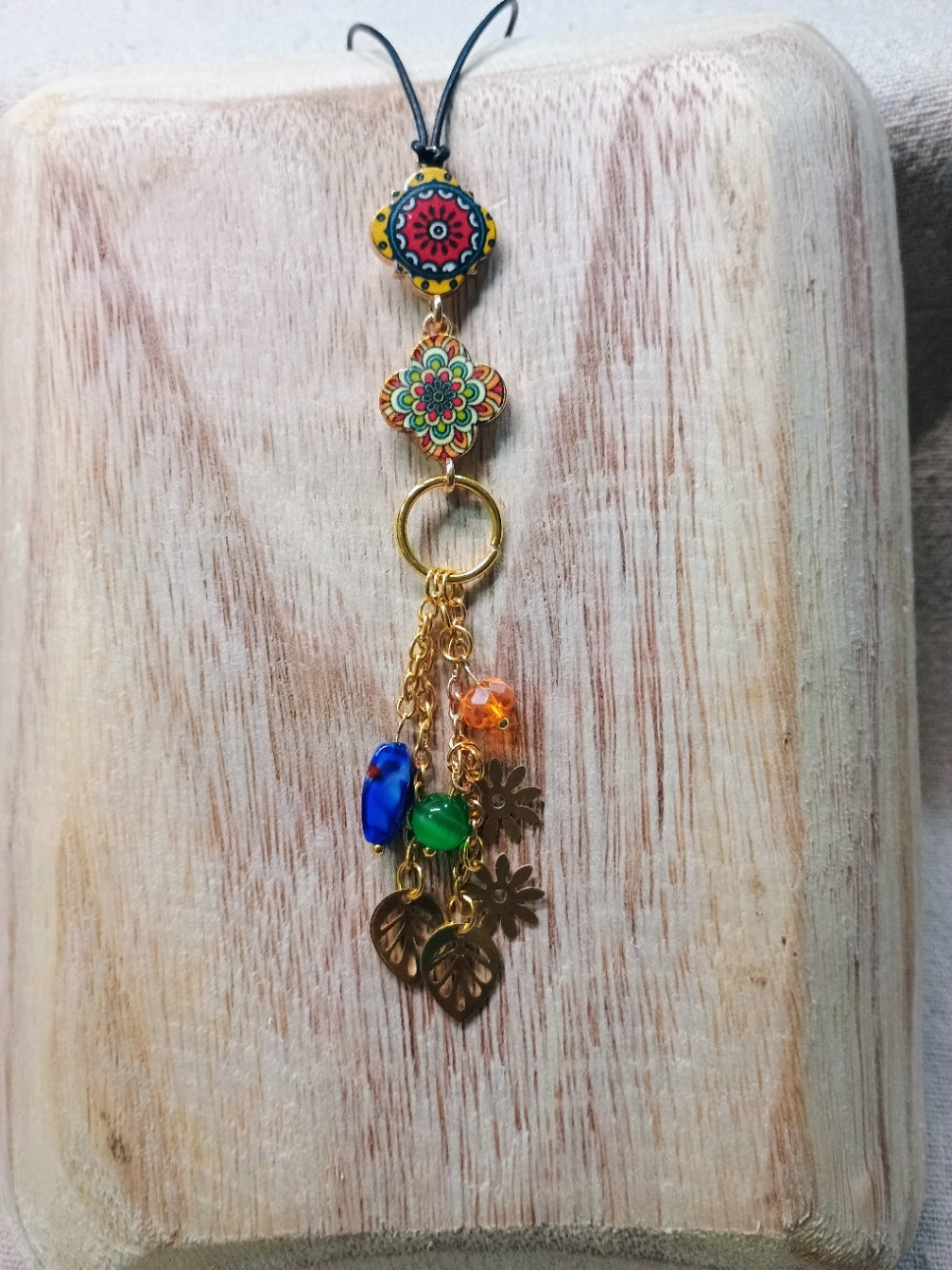 Colorful charm cascade with floral and circular designs on a wooden surface