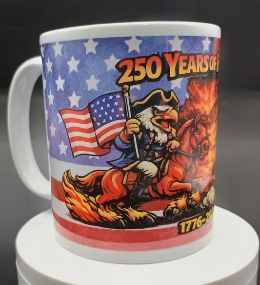 A white ceramic mug featuring a colorful patriotic graphic with the text '250 YEARS OF' and '1776-2026', showing an eagle riding a burning horse against an American flag background.