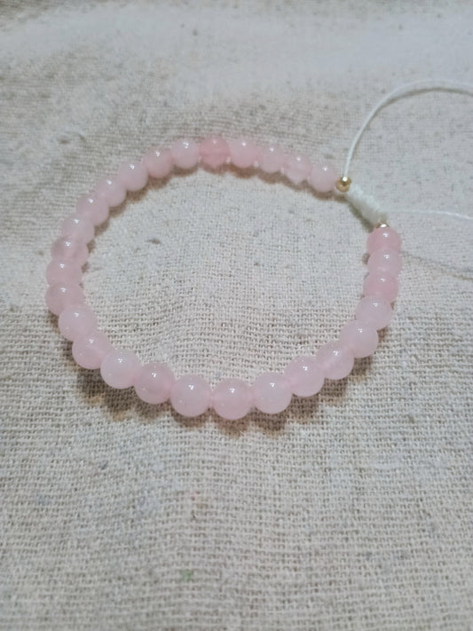 Handcrafted rose quartz bracelet on Brazilian wax cord, displayed on linen fabric