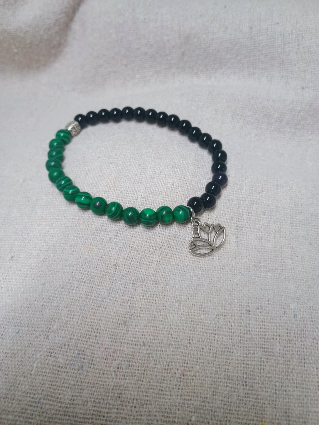 Green and black beaded bracelet with silver-tone lotus flower charm