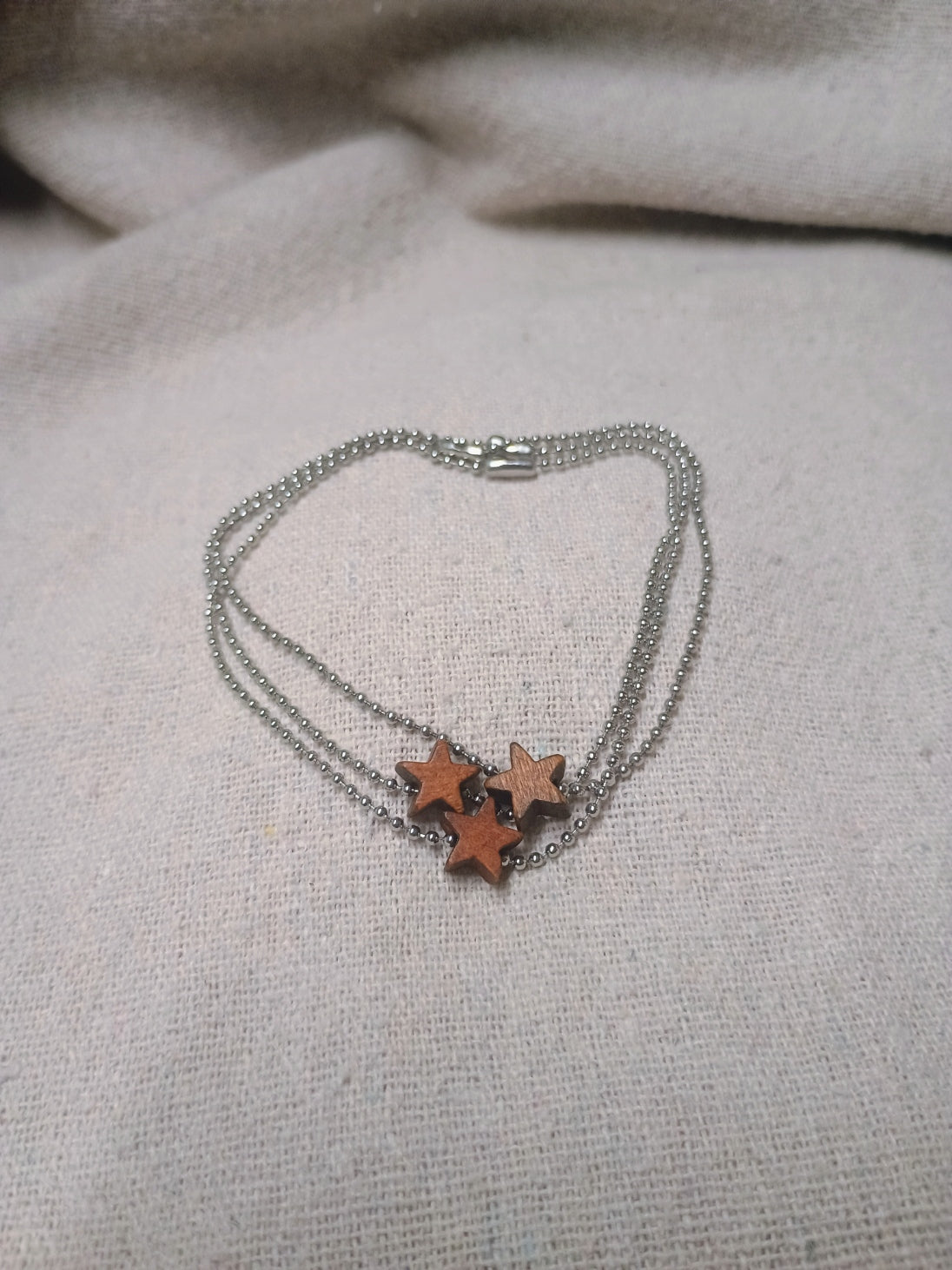 Three silver-tone ball-chain bracelets with floating brown wooden stars