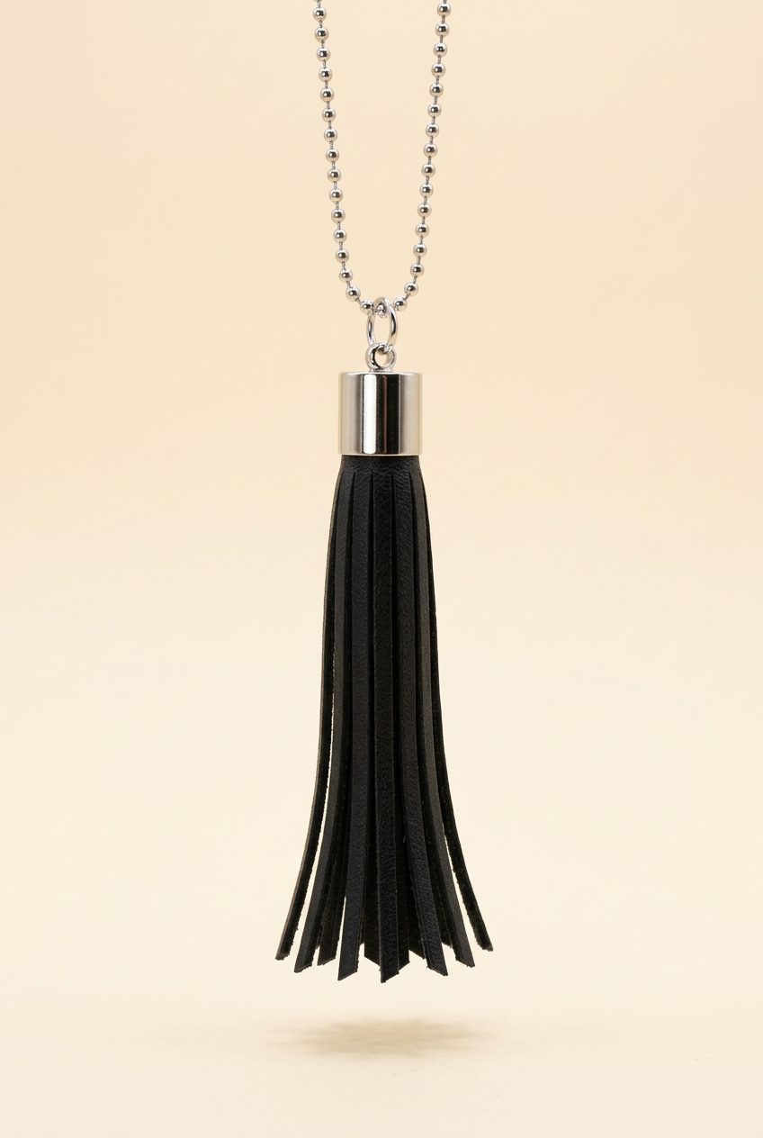 Black tassel and silver-tone ball chain on a clean cream background