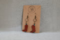 Cowboy boot earrings on a cardboard backing with a brand logo.
