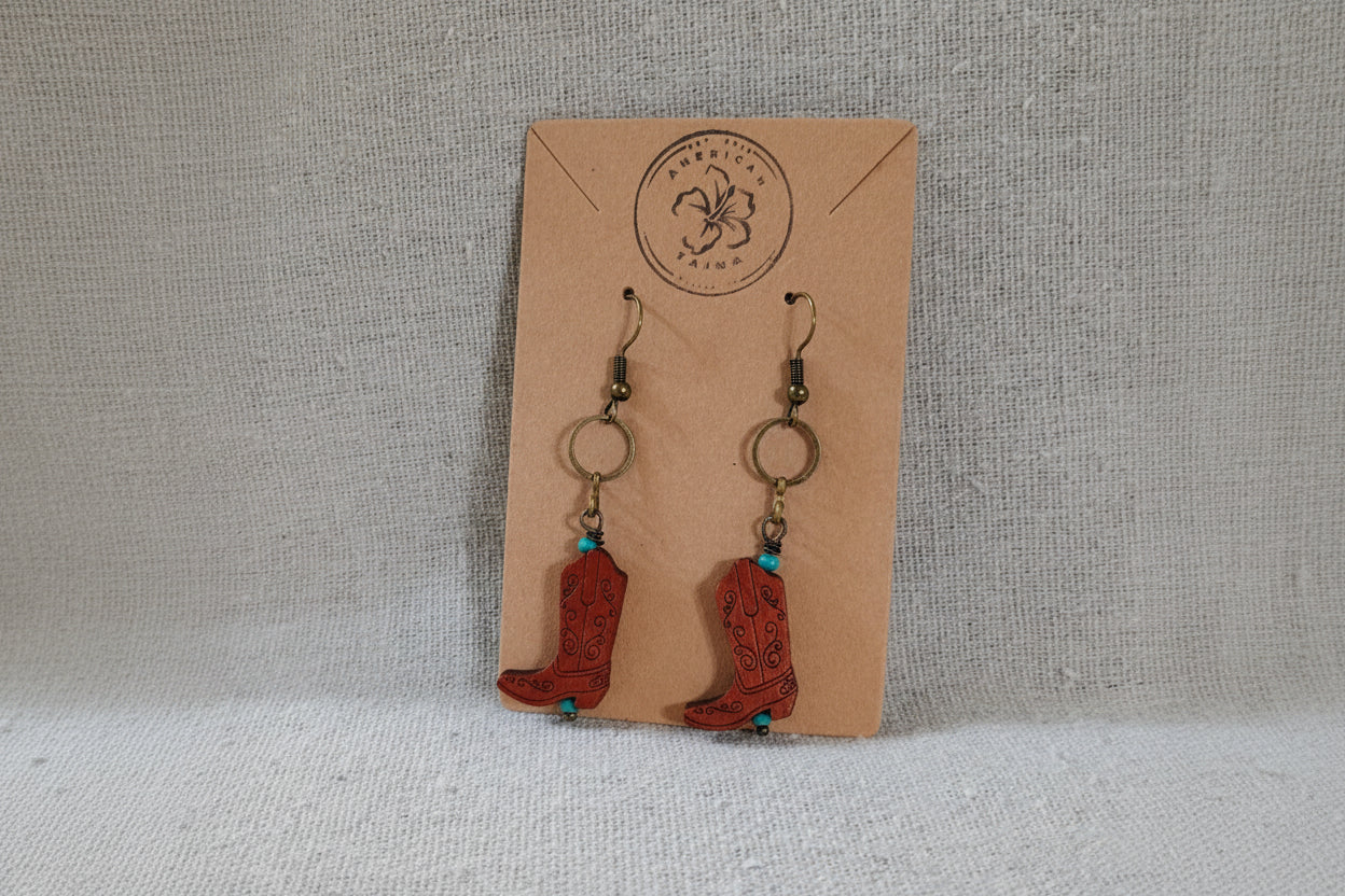 Cowboy boot earrings on a cardboard backing with a brand logo.