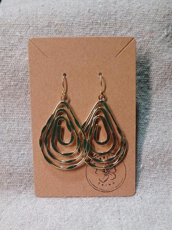 Gold-tone abstract layered hoop earrings on a brown card with a logo, displayed on fabric
