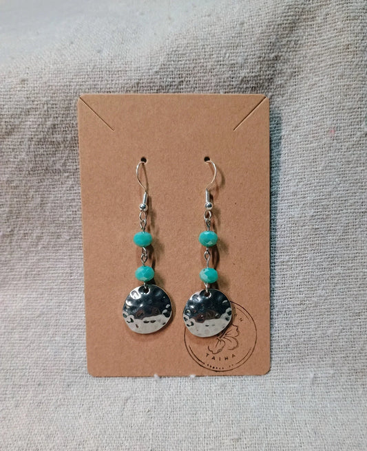 Handmade dangle earrings with hammered silver discs and two turquoise beads on brown card
