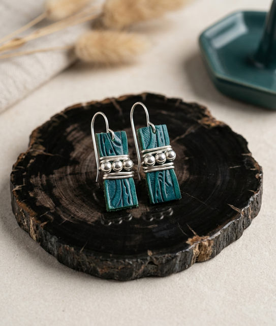 Teal tooled leather drop earrings with silvertone hematite beads across the center