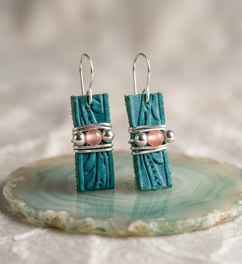 Teal tooled leather drop earrings with pink rose quartz beads at the center