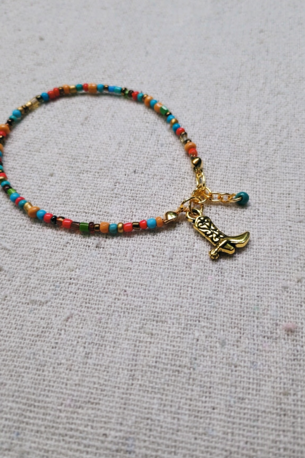 Colorful beaded bracelet with a gold boot charm on a light gray background