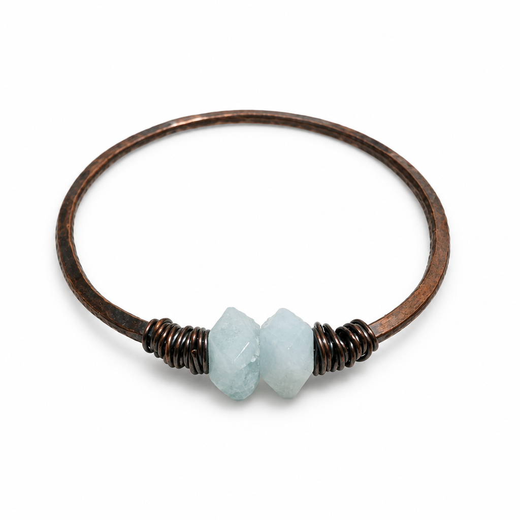 Pale aquamarine and oxidized copper bangle with coiled accents on a white background.