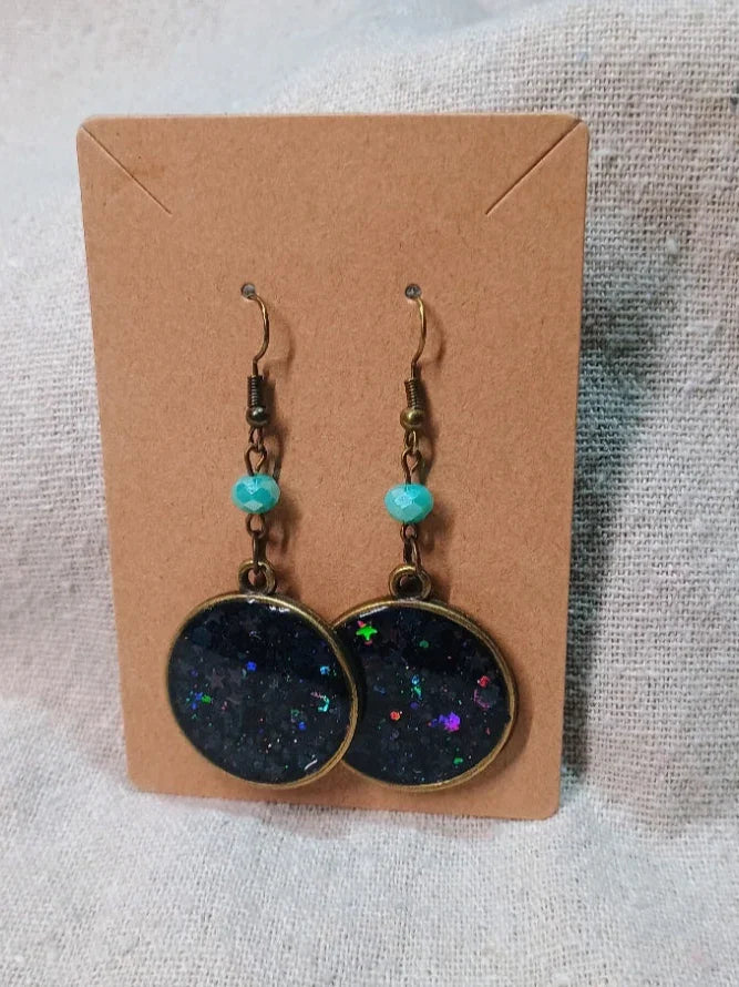 Handmade dangle earrings with blue beads and round black resin pendants with colorful glitter