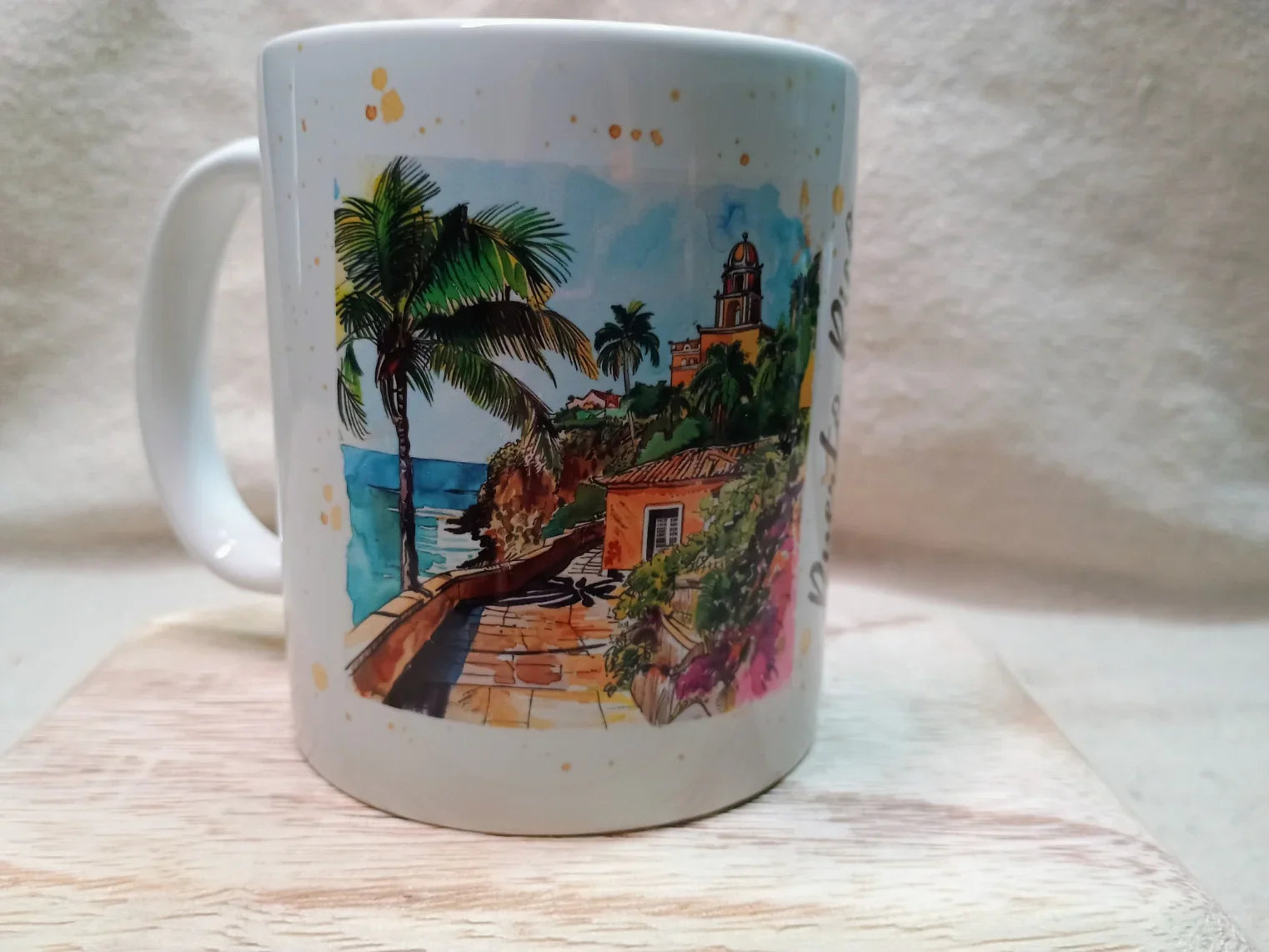White mug with colorful tropical beach scene featuring palm trees, ocean, walkway, and buildings