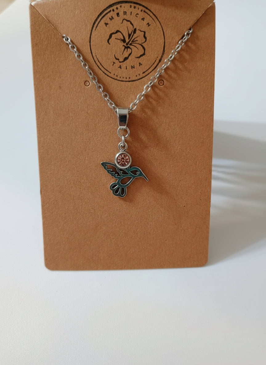 Silver hummingbird pendant necklace with a pink gemstone on brown American Taina Crafts card