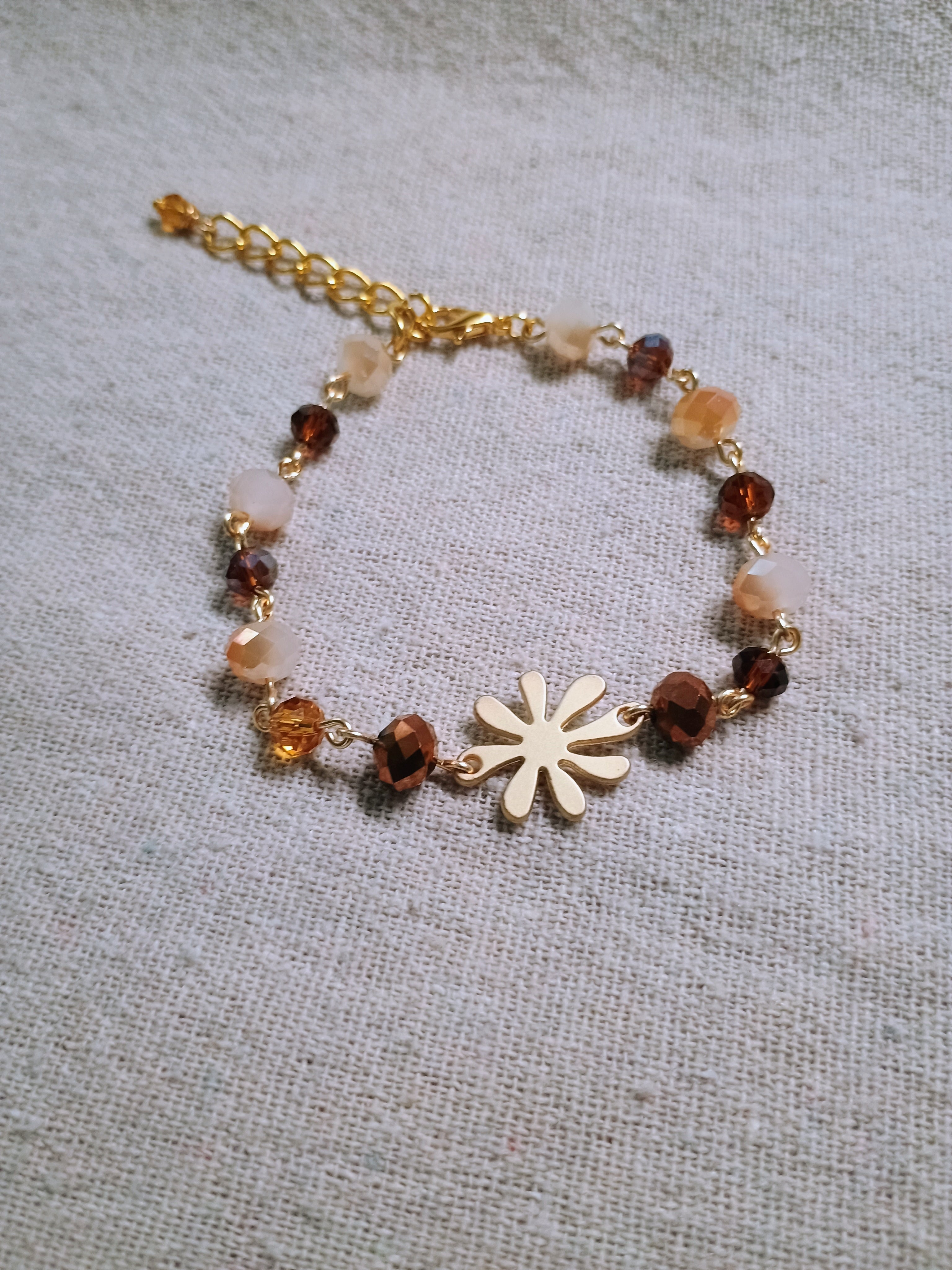 Bracelet with beads and a flower charm on a textured fabric background