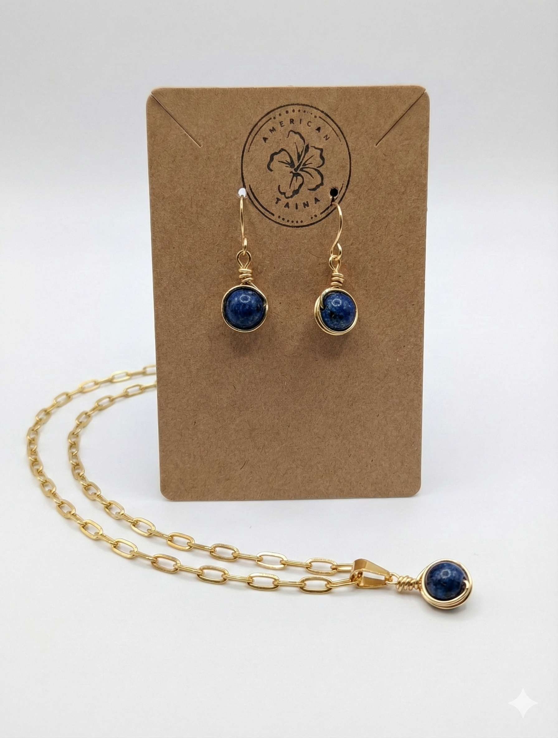 Handcrafted gold wire earrings and matching pendant necklace with deep blue stone on brown card from American Taina Crafts