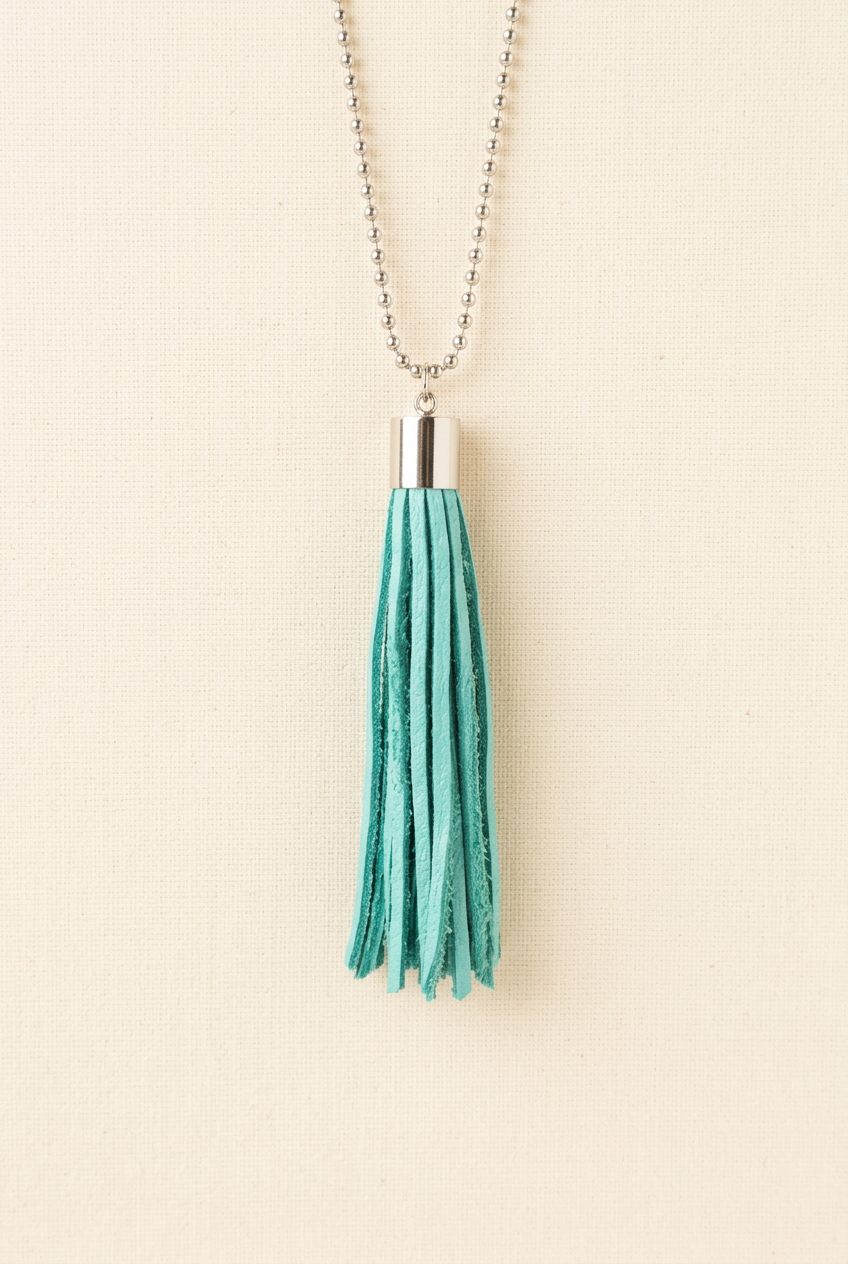 Turquoise tassel with silver-tone cap and ball chain on a clean cream background
