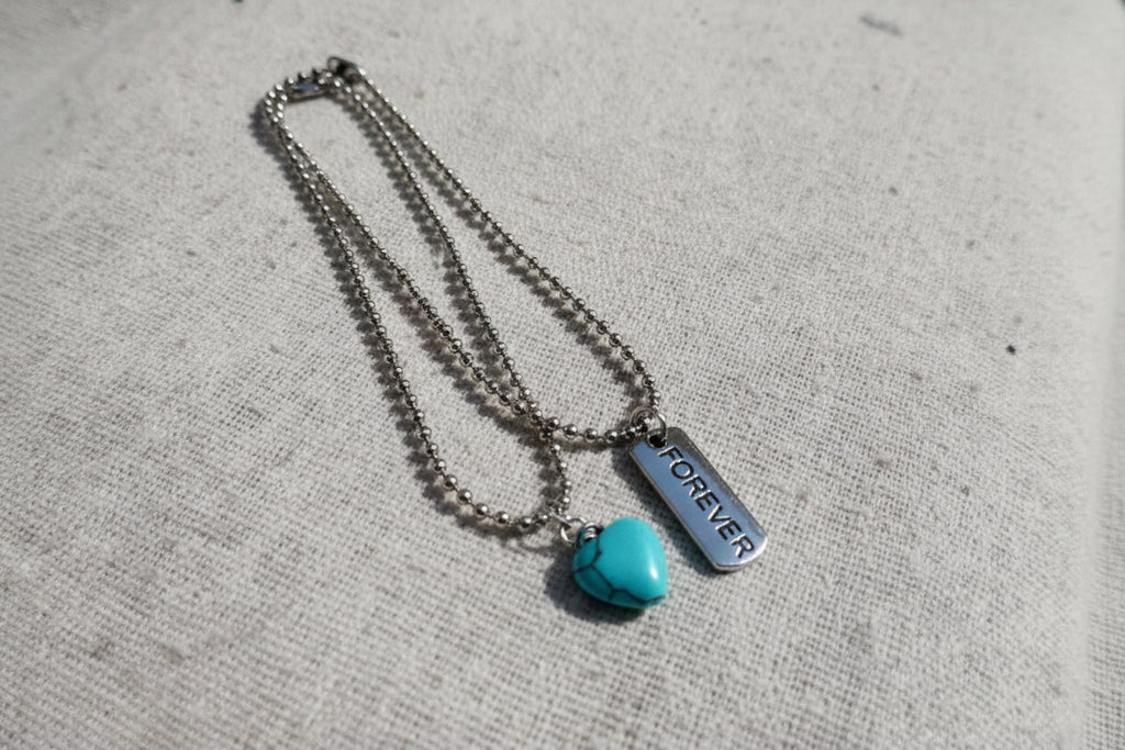 bracelet with a turquoise pendant and 'FOREVER' tag on a textured surface
